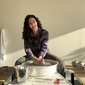 Woman joyfully laughing while at a pottery wheel at Handful Studios in Portland