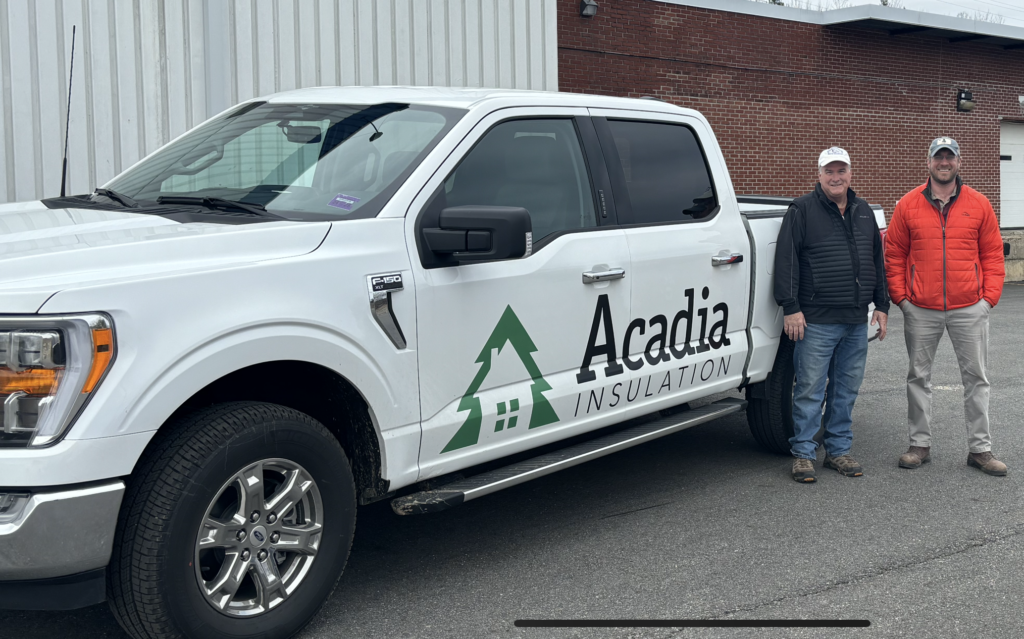 Acadia Insulation logo on white truck with two men standing in front
